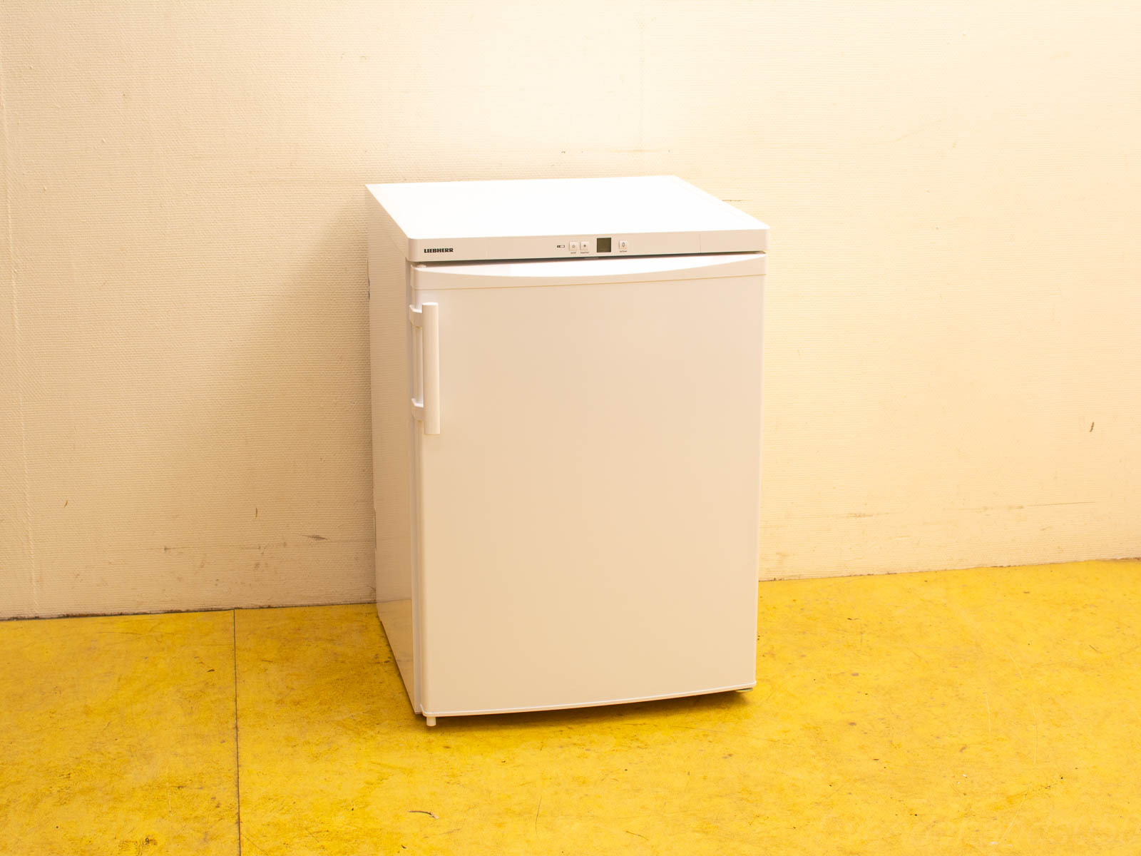 Compact white refrigerator with modern design, perfect for small spaces and dorm rooms on a vibrant yellow floor.