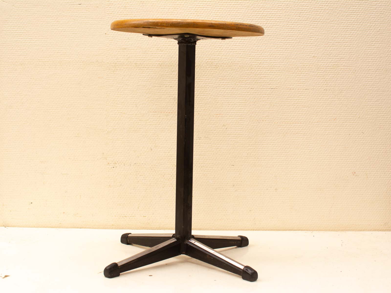 Stylish minimalist stool with light wooden seat and sturdy black metal base, ideal for various settings.