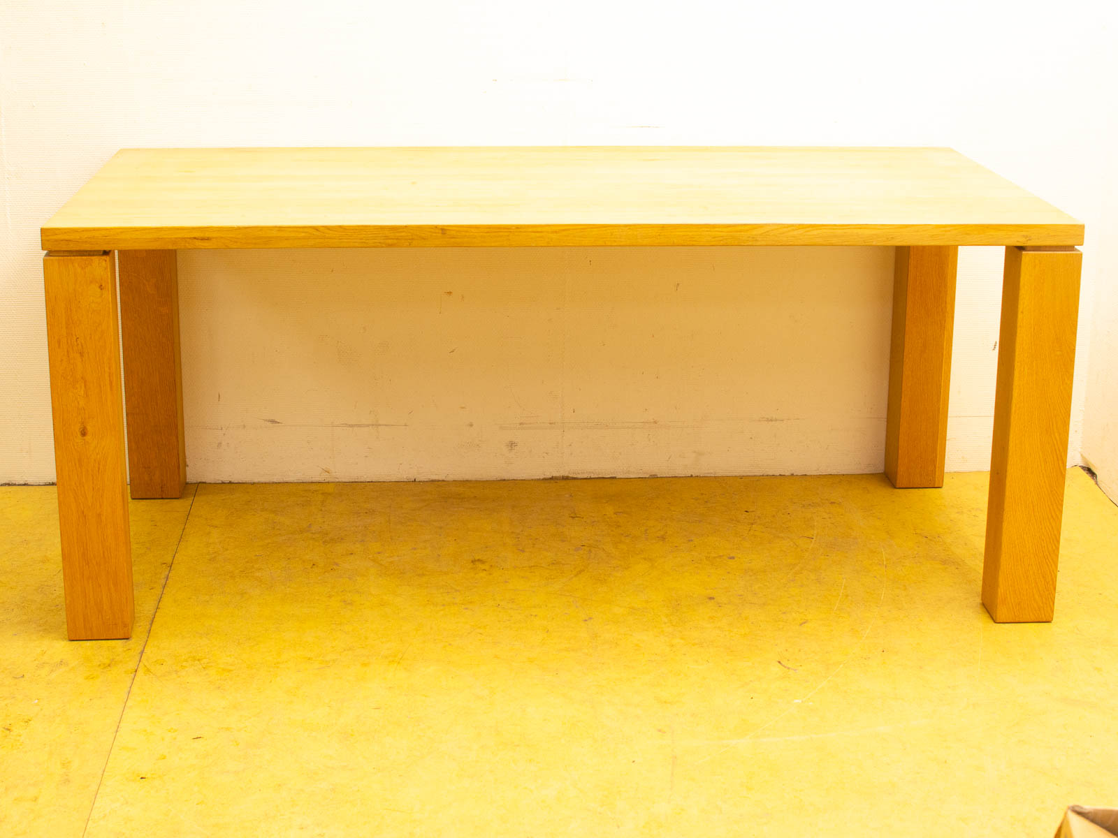 Stylish, minimalist wooden table on vibrant yellow floor, perfect for modern kitchens or office spaces.