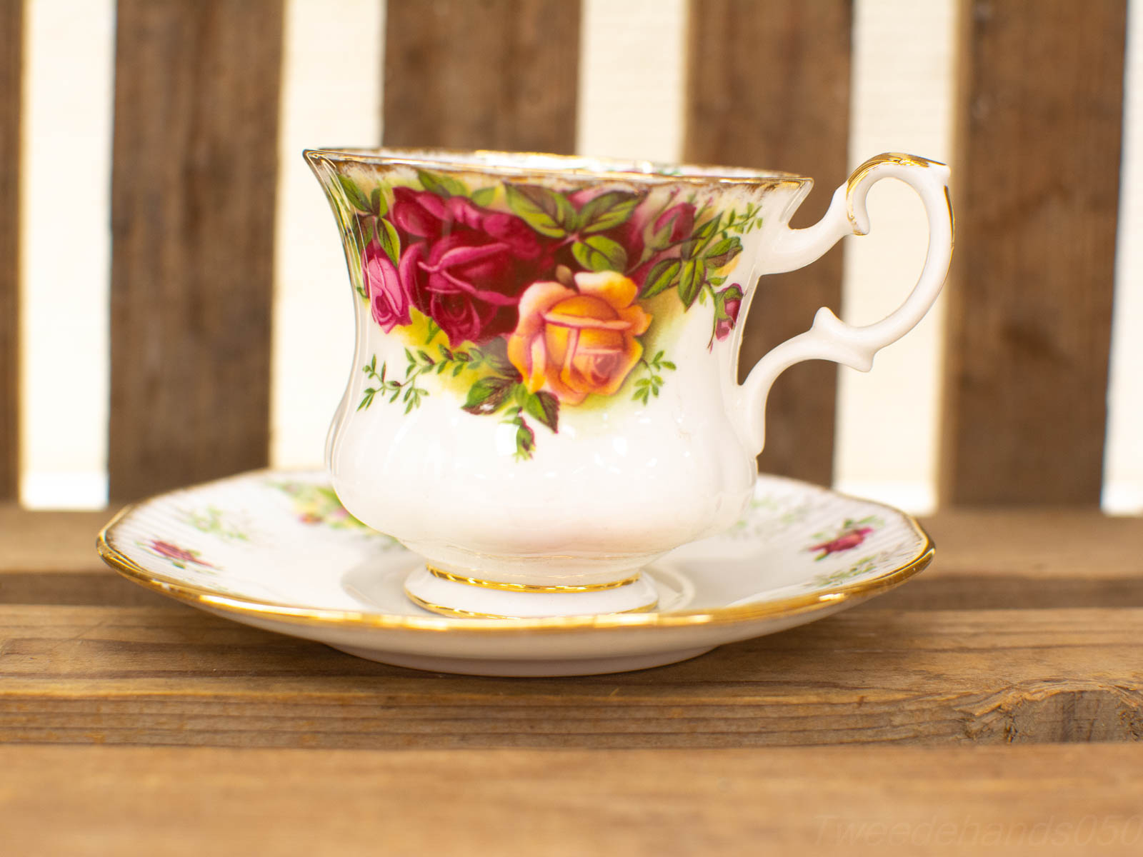 Vintage porcelain tea cup and saucer set featuring vibrant floral designs on a rustic wooden backdrop.