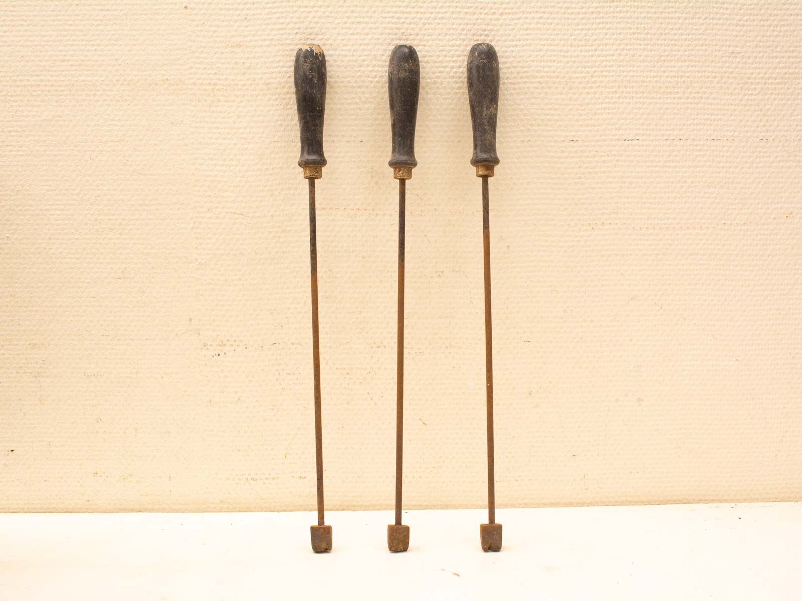 Vintage craftsmanship tools with square metal tips and weathered wooden handles for precision work.