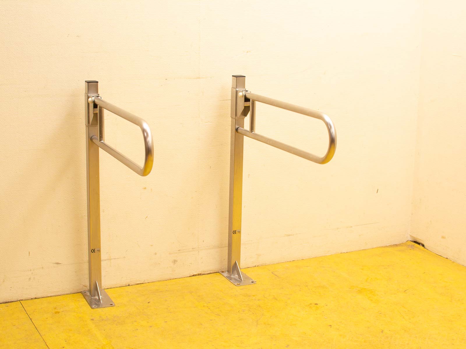 Modern stainless steel handrails on a light wall with bold yellow floor for enhanced safety.