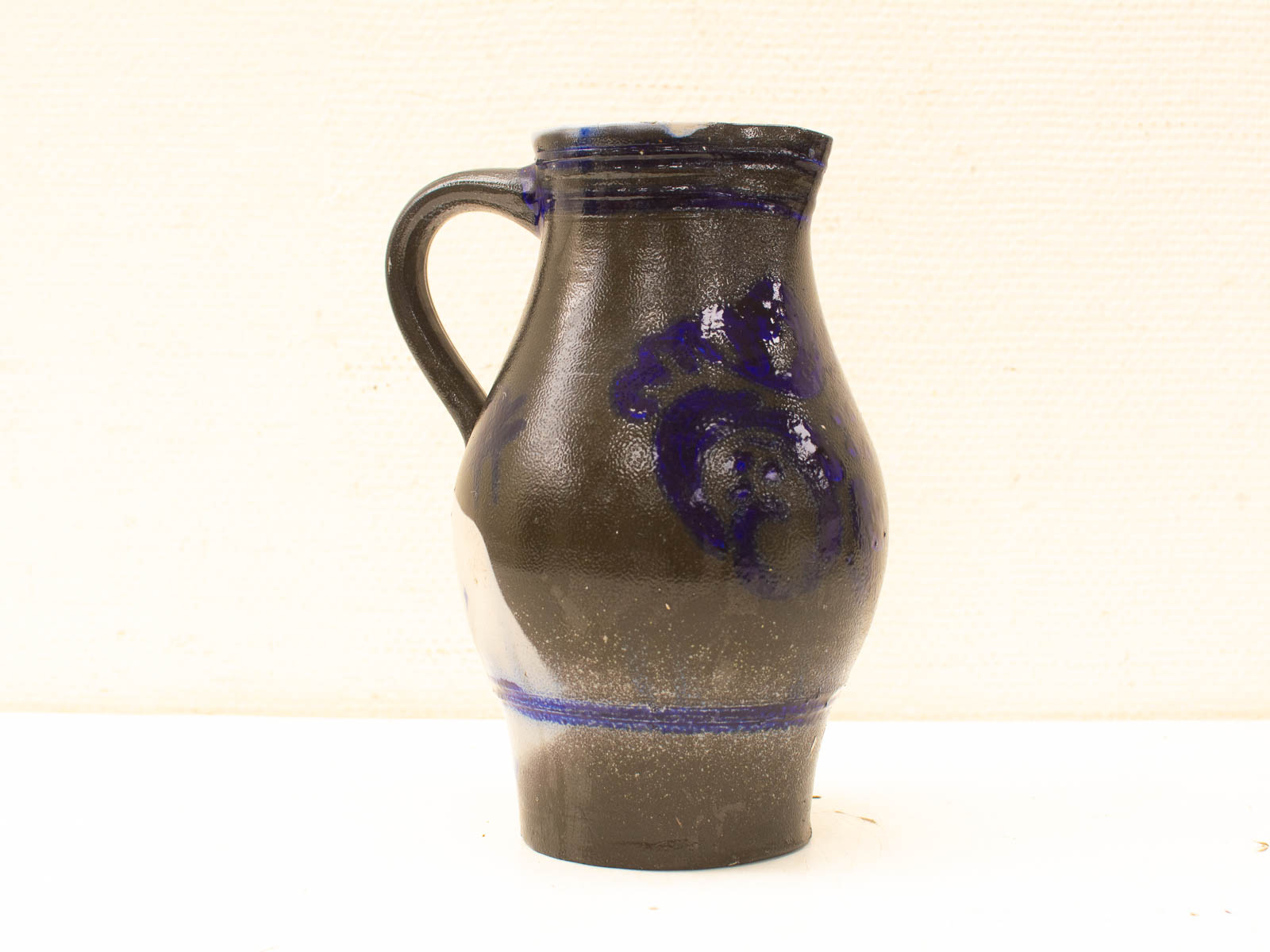 Elegant Hand-Painted Ceramic Jug with Vibrant Blue Motifs on a Glossy Black Surface