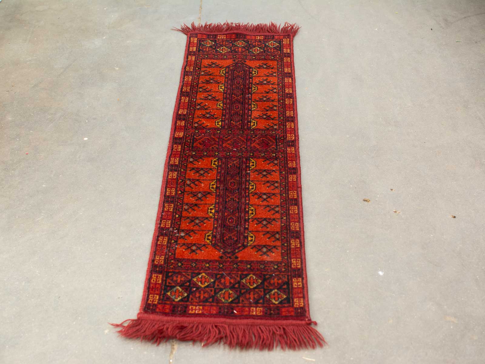 Vibrant red traditional rug with intricate geometric patterns and floral motifs on a neutral floor.