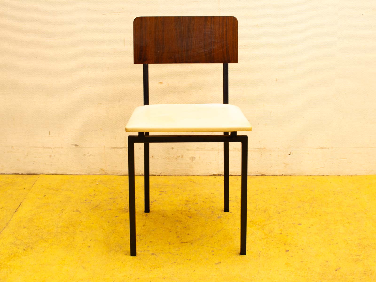 Sleek minimalist chair with wooden backrest and black metal legs for modern interiors.