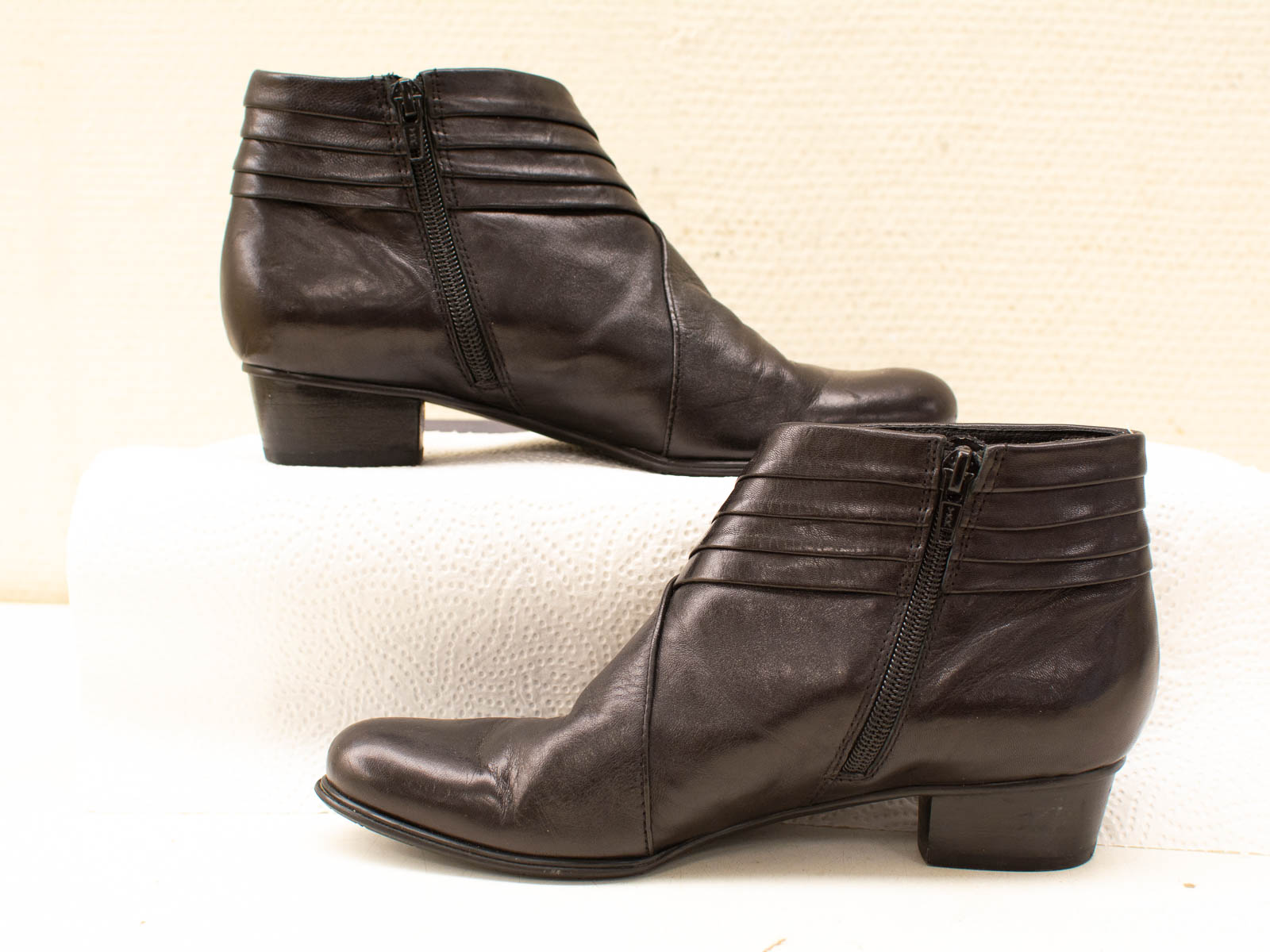 Stylish black ankle boots with pleating and zip closure for versatile, elegant outfits.