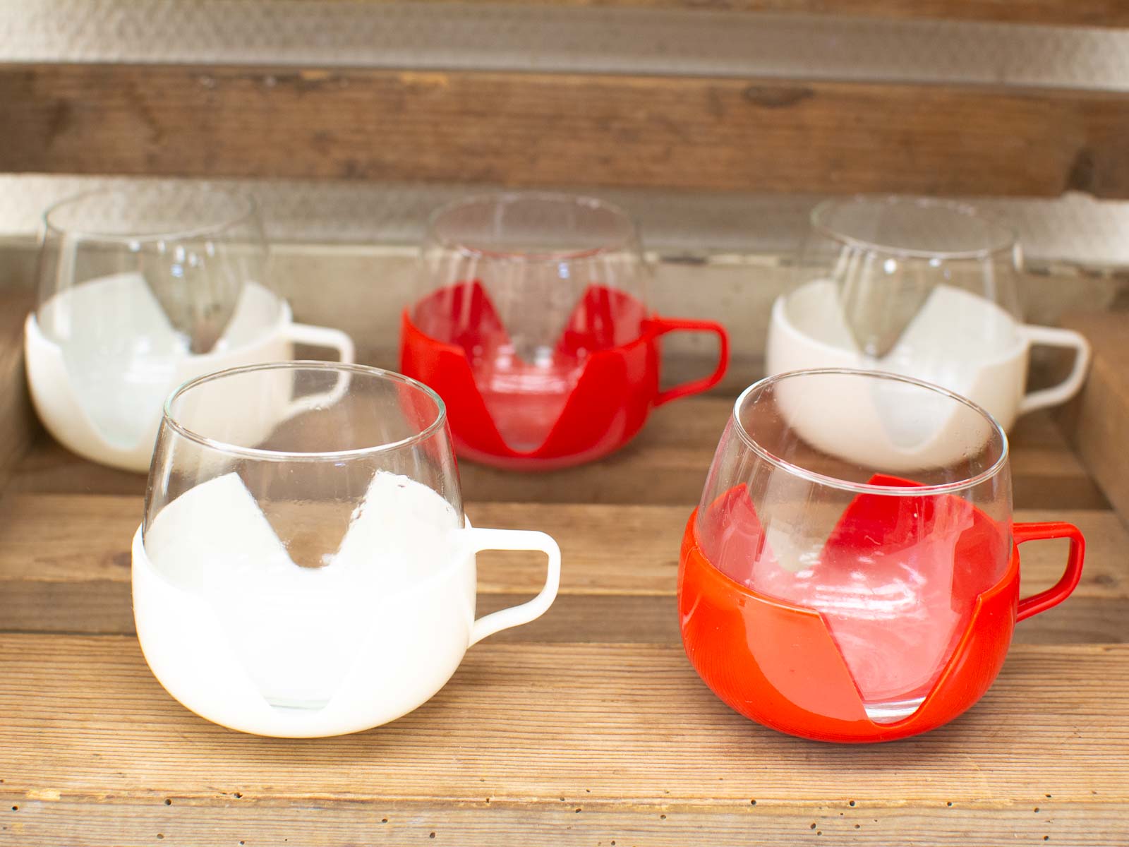 Colorful vintage cups on a rustic wooden table, perfect for casual dining or coffee breaks.