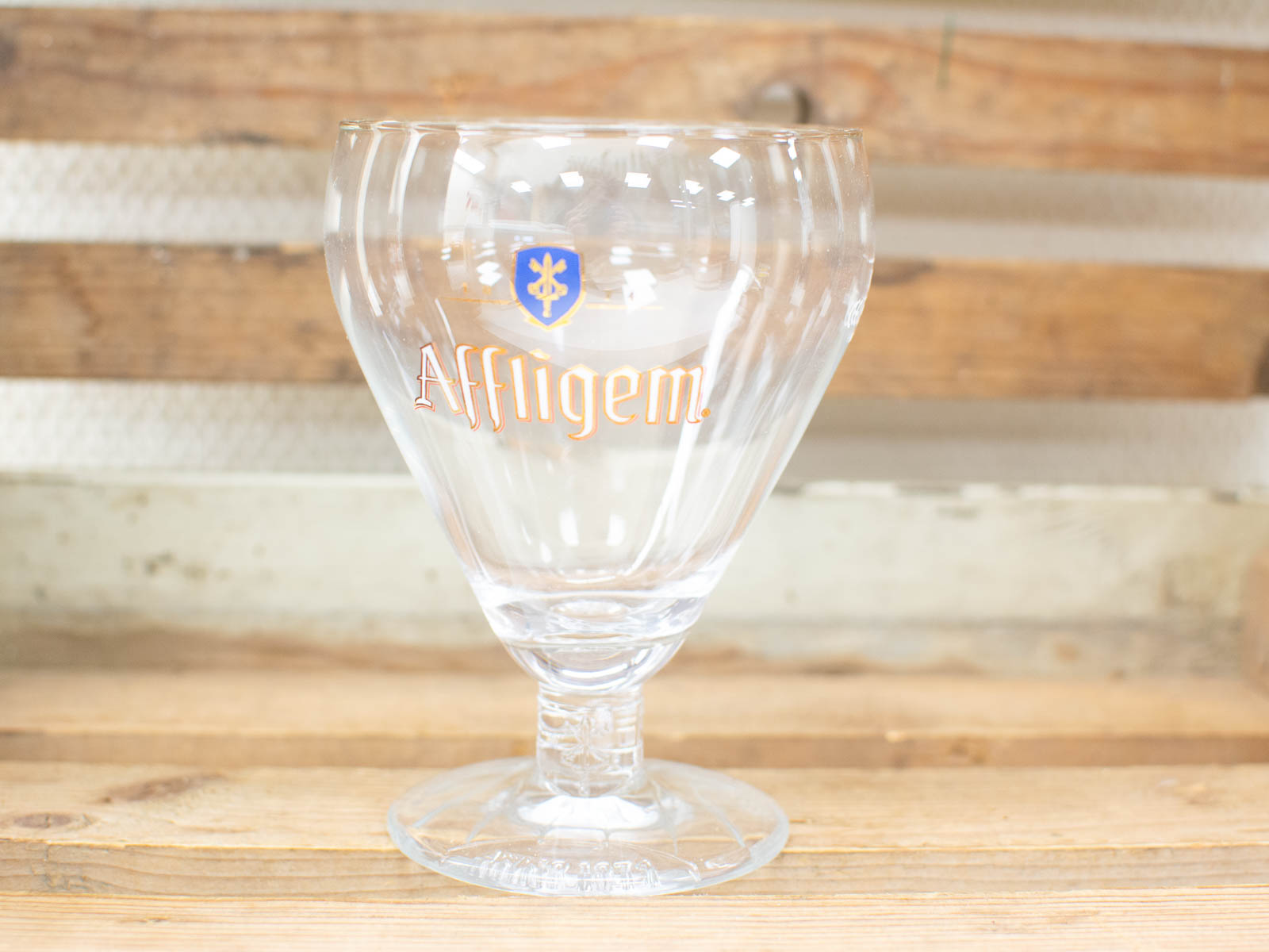 Elegant Affligem beer chalice on rustic wood, perfect for savoring rich beer flavors.