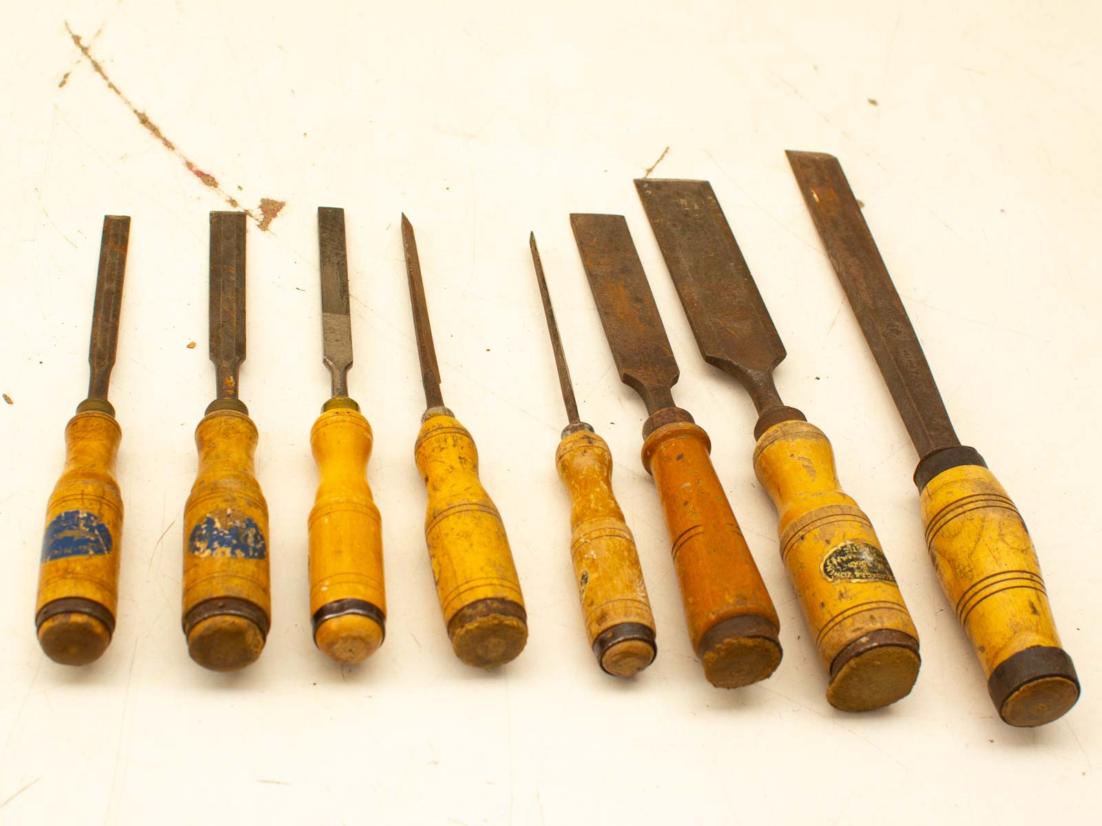 Vintage woodworking chisels with character, showcasing worn handles and diverse blade sizes.