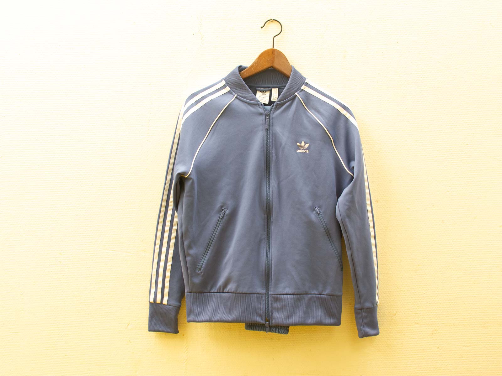 Stylish secondhand adidas blue track jacket with cream stripes, perfect for casual or athletic wear.