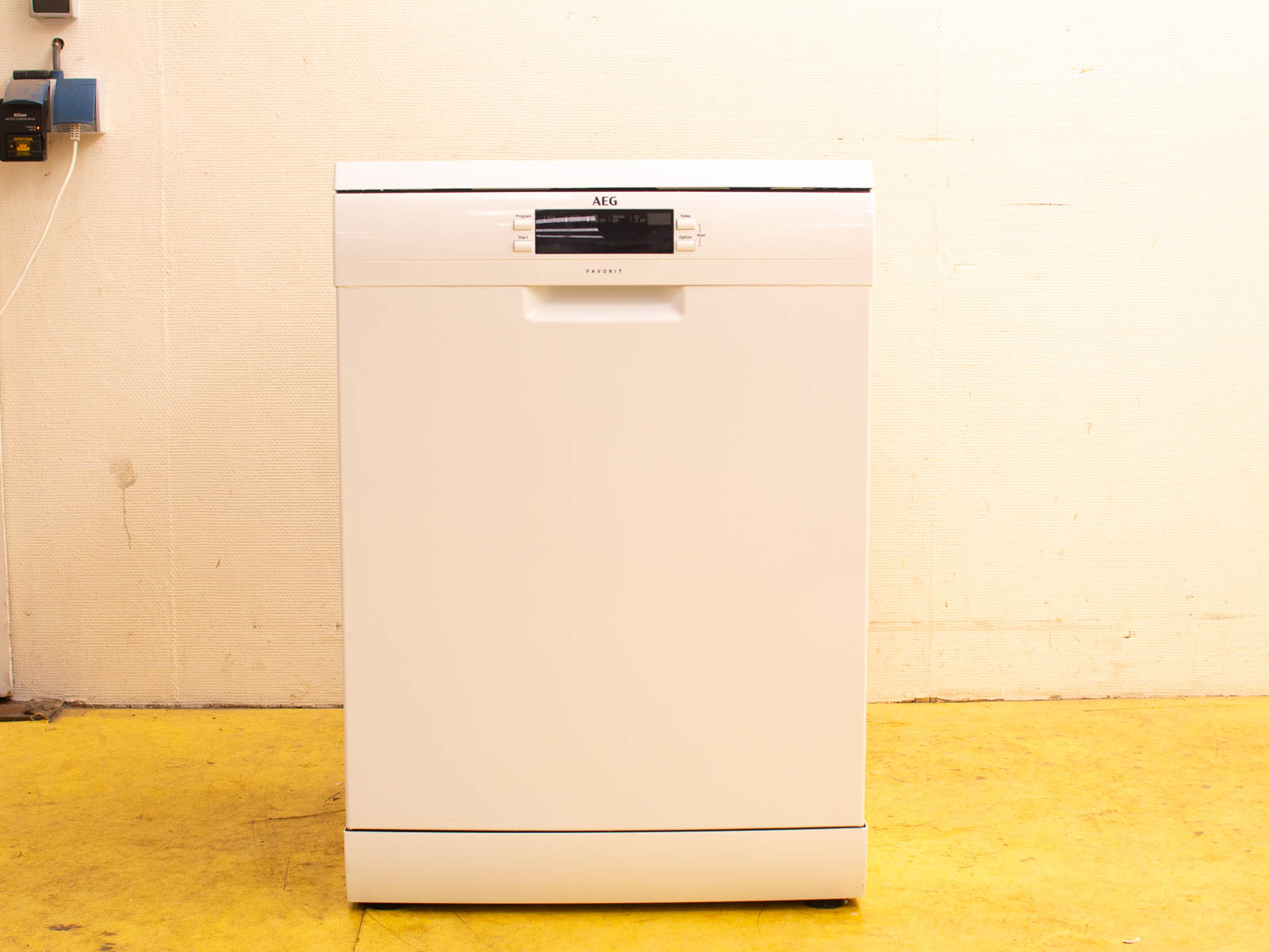 Sleek white AEG dishwasher on vibrant yellow floor, enhancing modern kitchen style and efficiency.