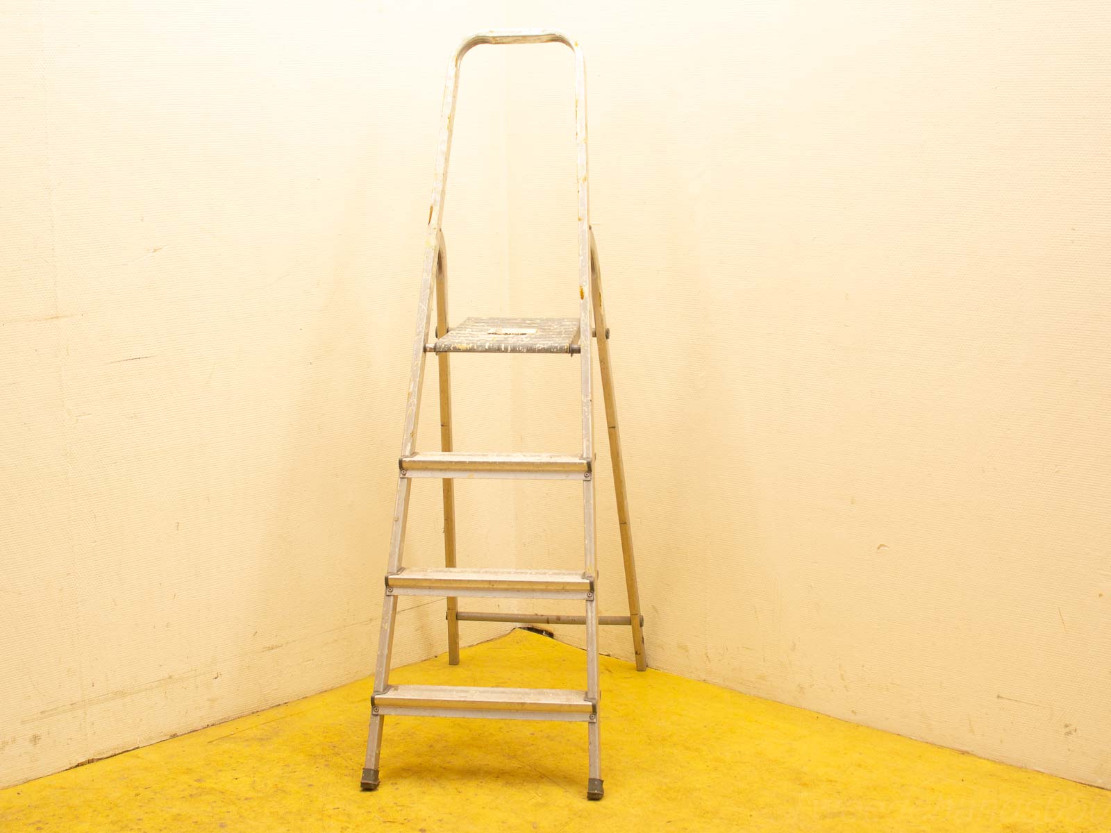 Aluminum step ladder in a warm corner, ideal for home tasks and easy access.