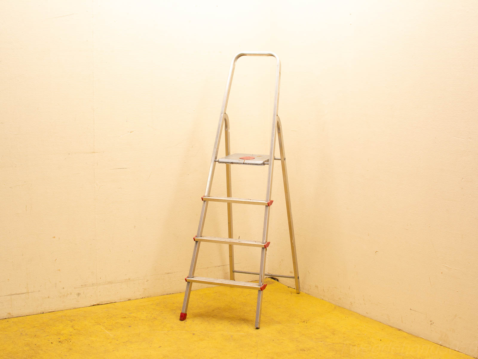 Aluminum step ladder with non-slip steps in a warm-toned utility room.