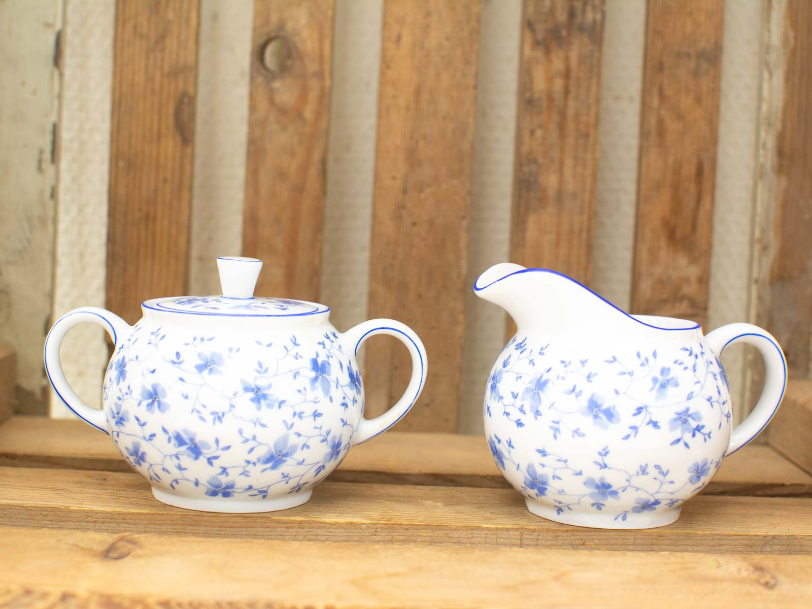 Charming porcelain sugar bowl and cream jug with blue floral patterns, perfect for tea service.