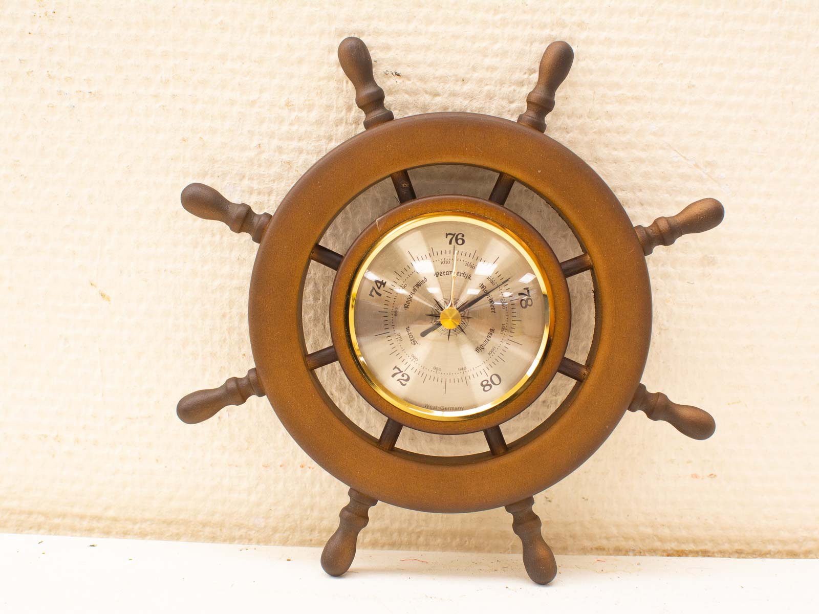 Nautical wooden wall clock design resembling a ships steering wheel with barometer features.