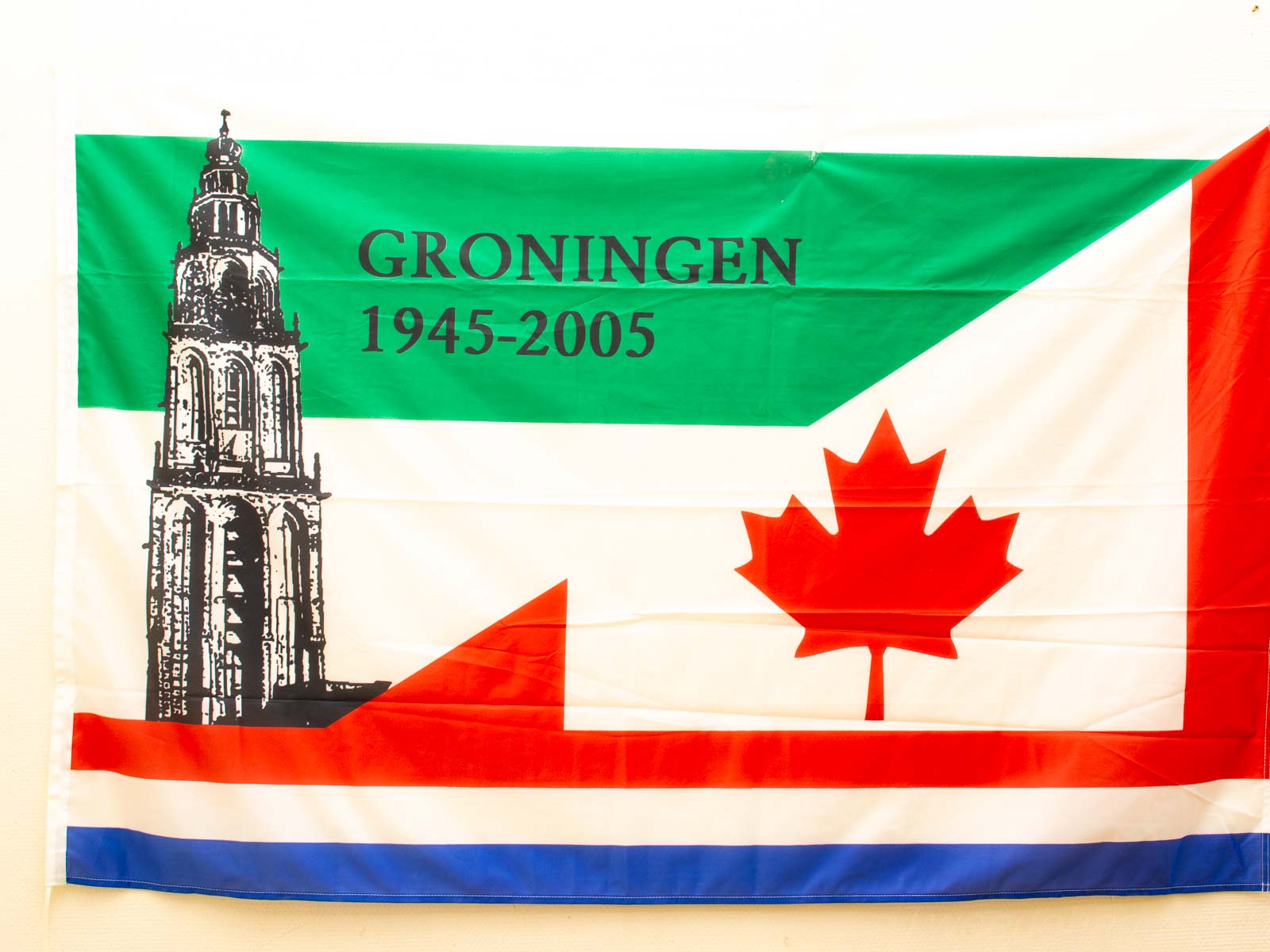 Groningen-Canada flag unites cultures, celebrating heritage with the Martinitoren and a maple leaf.