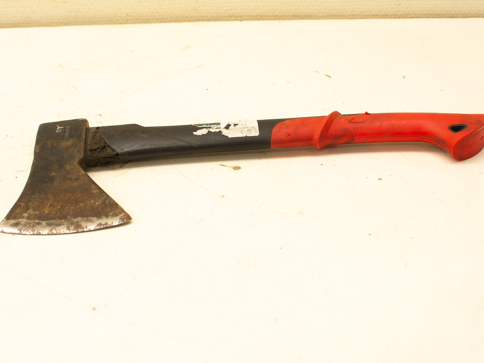 Sturdy hand axe with rustic blade, ergonomic black handle, and vibrant red grip for outdoor use.