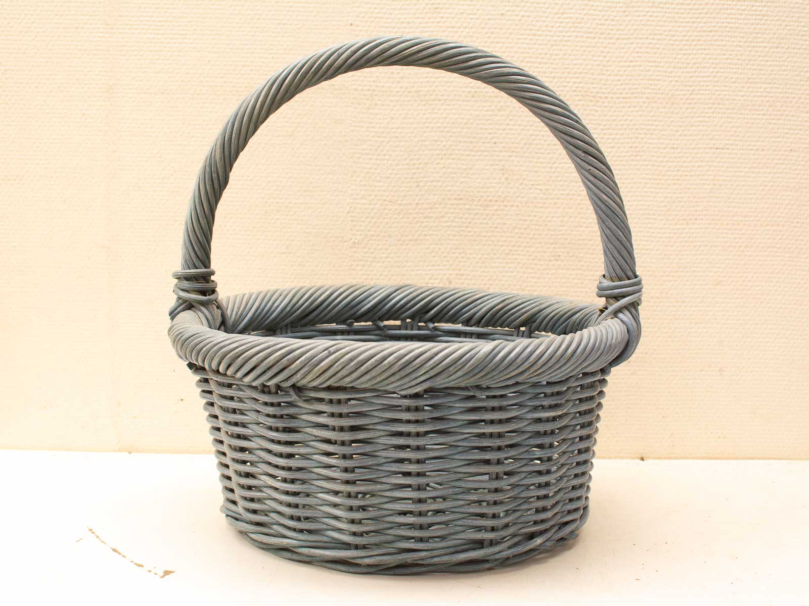 Gray handwoven rattan basket with sturdy handle, perfect for decorative and practical storage.