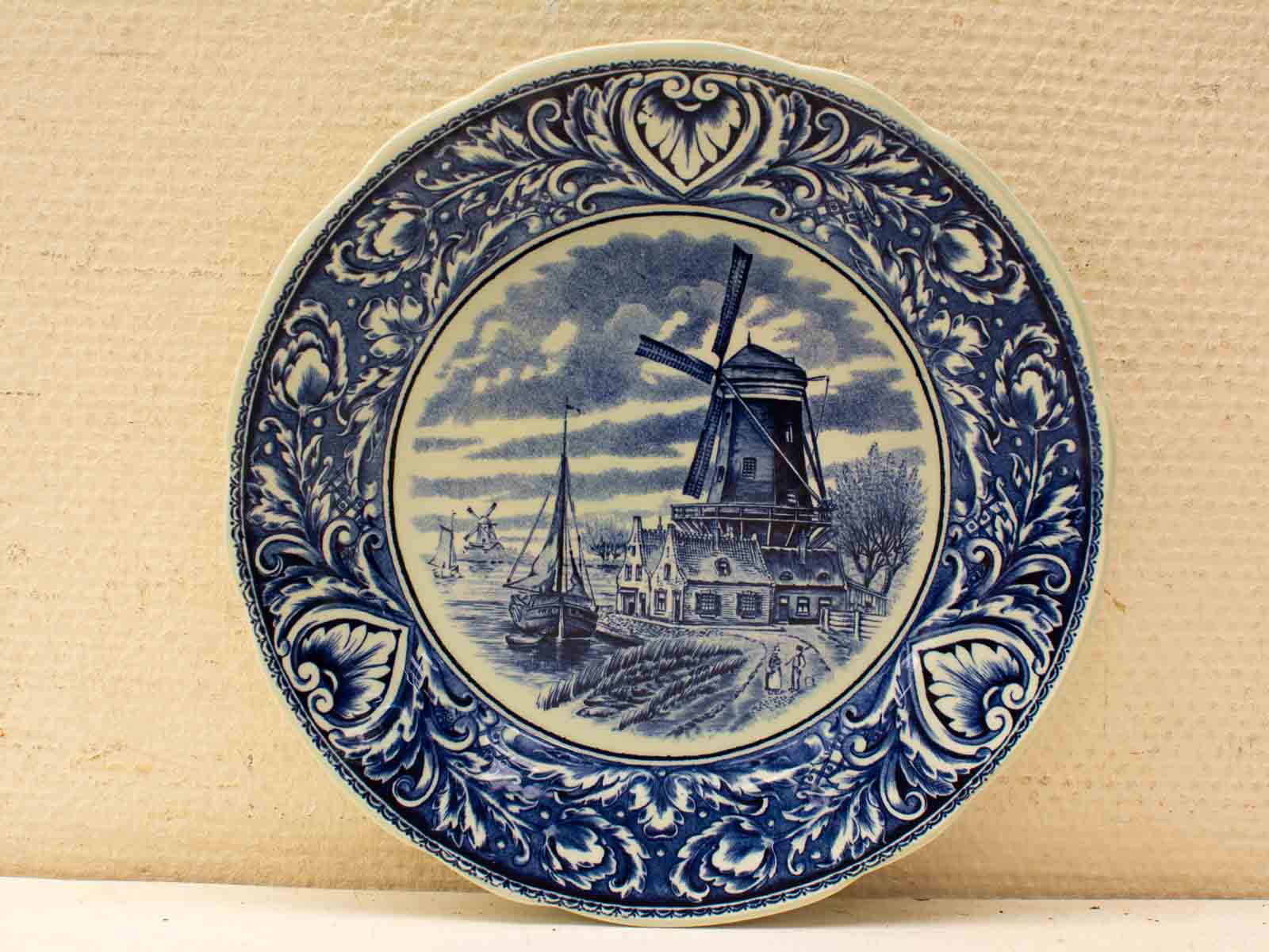 Delftware plate showcasing a Dutch landscape with a windmill, village, and tranquil waterway.