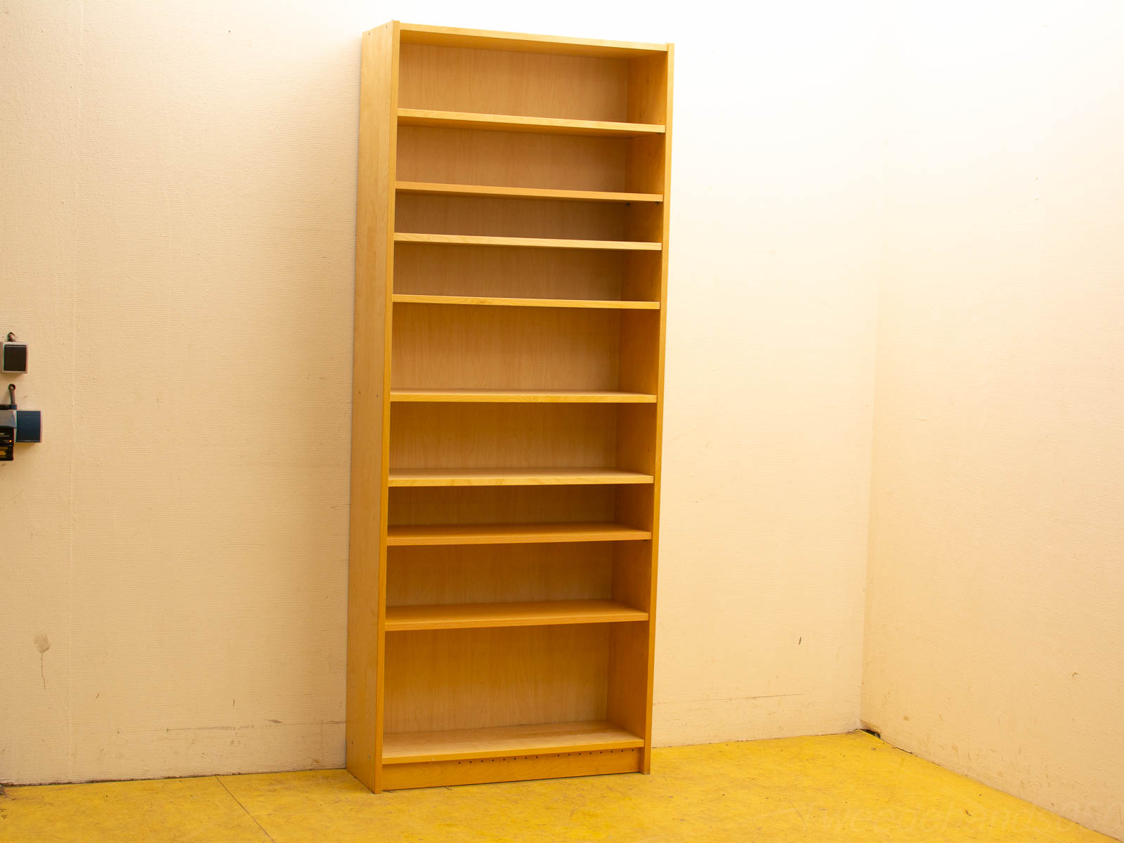 Light-wood, minimalist bookshelf against a pale wall, offering versatile storage for home, office, or library.