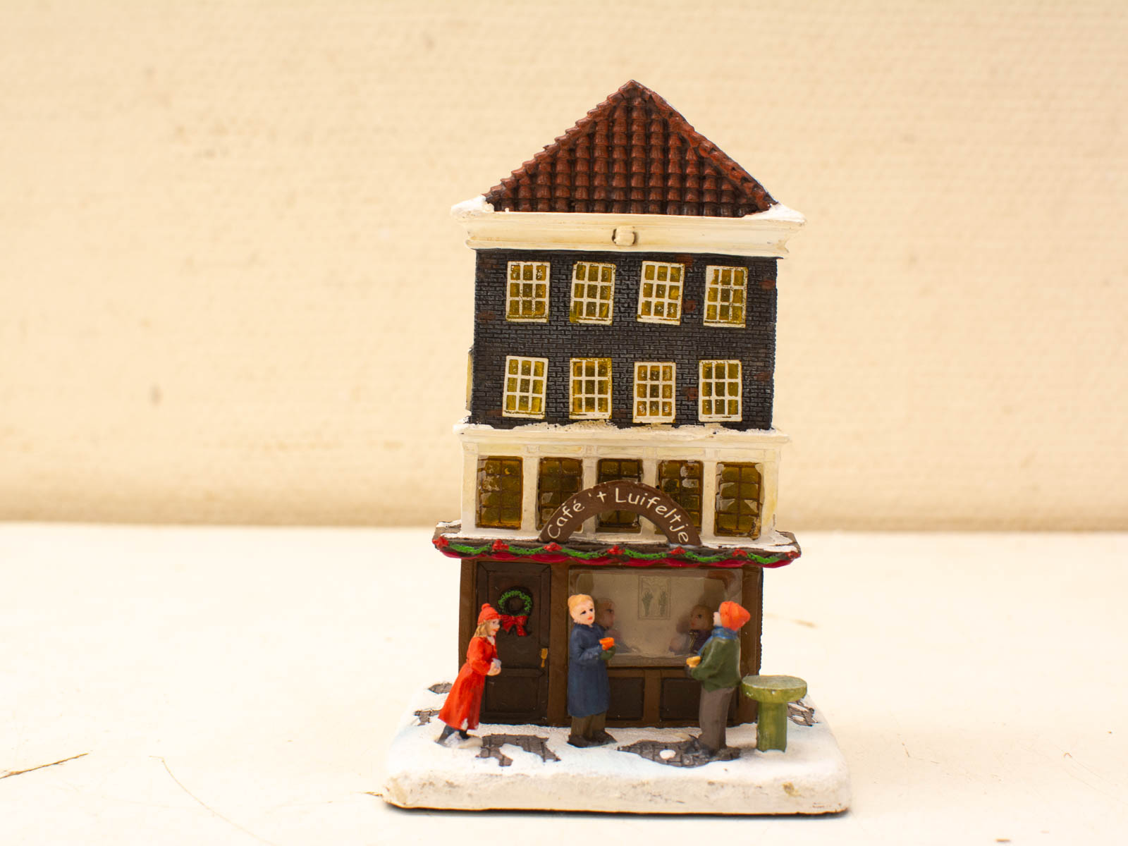 Charming miniature café scene with festive details and lively figures, perfect for winter gatherings.