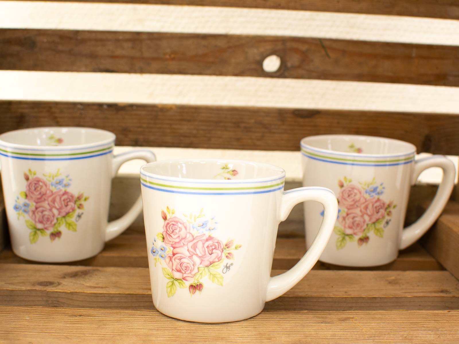 Charming floral ceramic mugs on rustic wood, perfect for cozy tea or coffee moments.