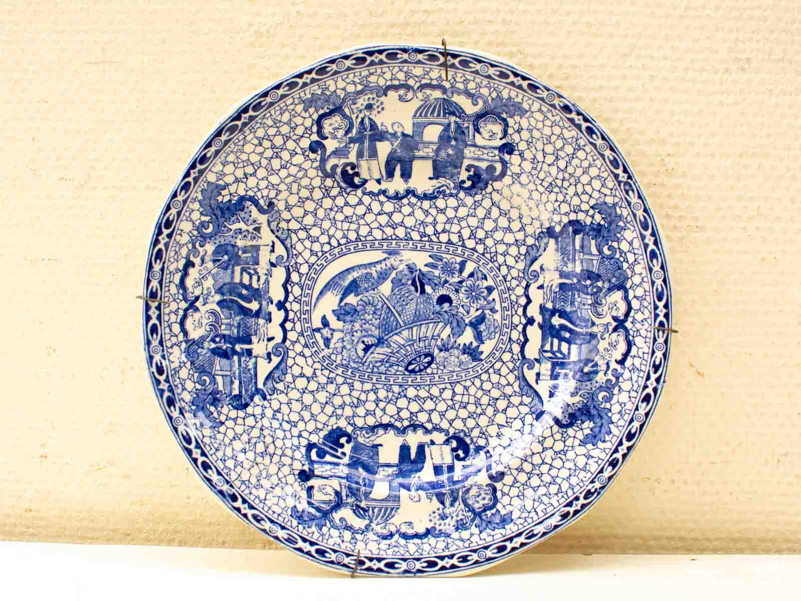 Elegant blue-and-white ceramic plate with intricate nature motifs and glossy finish.