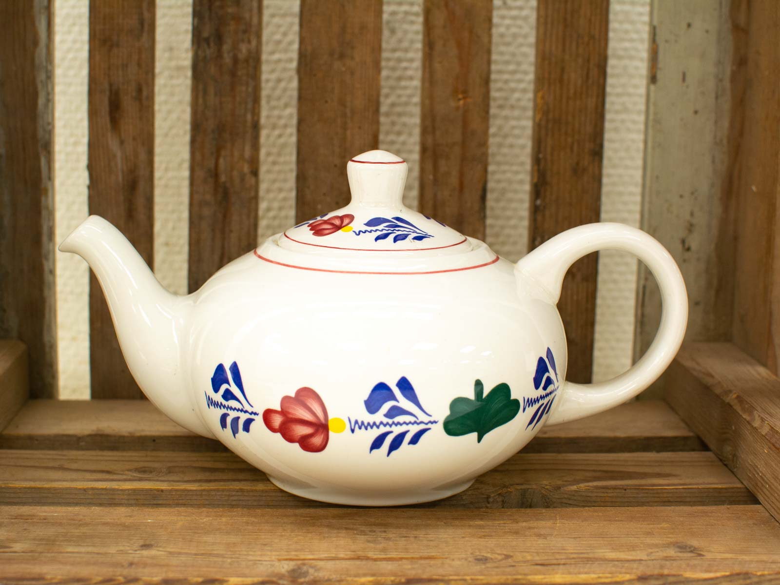 Elegant floral ceramic teapot on rustic wood, perfect for serving tea and enhancing decor.