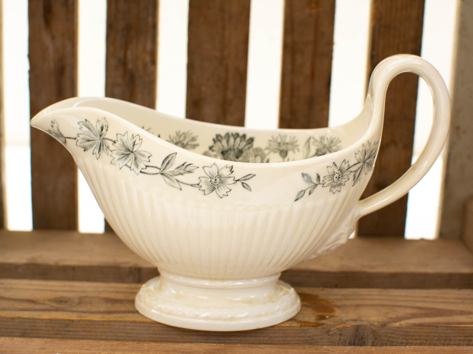 Elegant ceramic gravy boat with floral patterns, glossy finish, perfect for any kitchen setting.