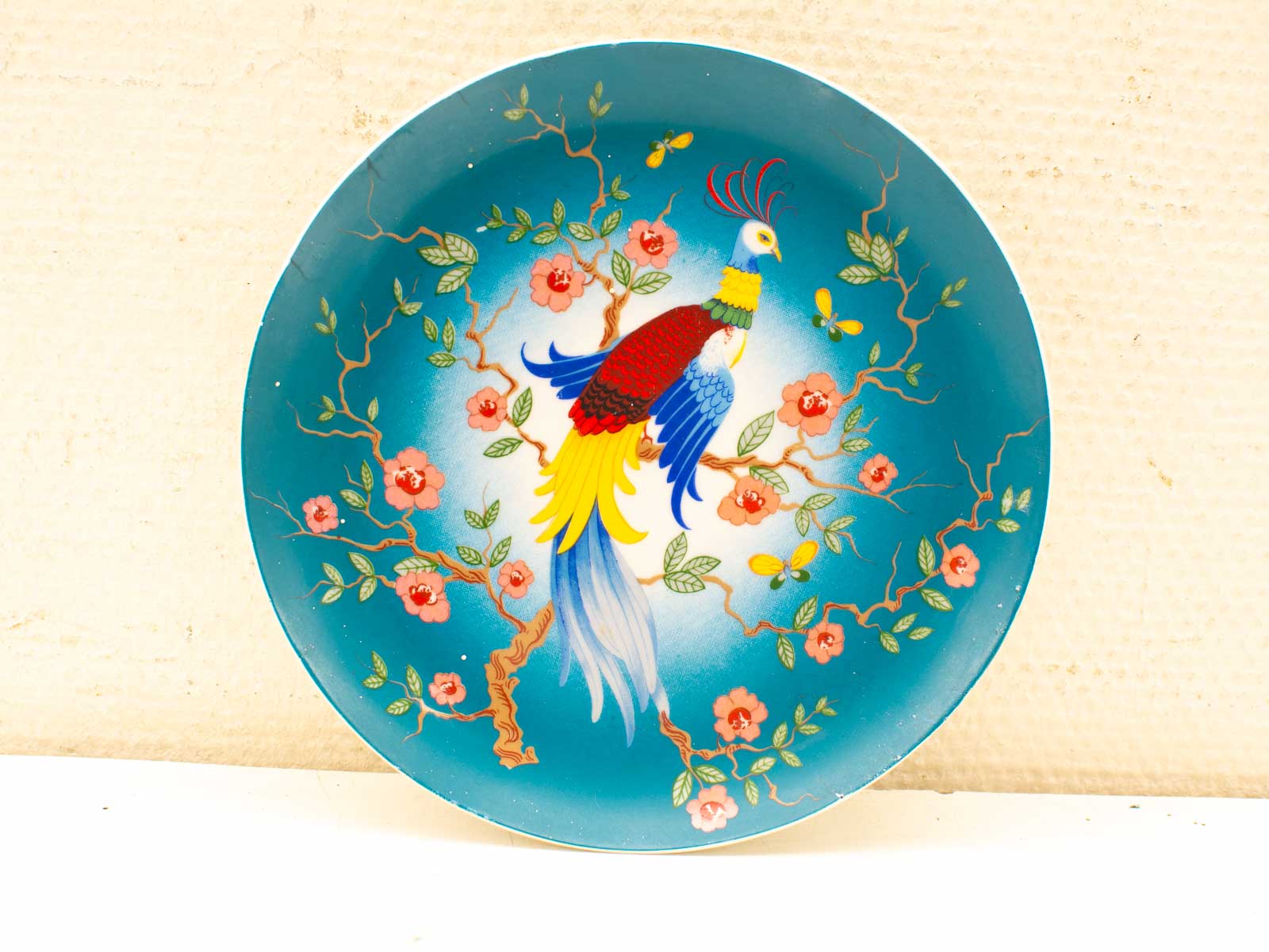 Colorful peacock decorative plate with flowers and butterflies, perfect for stylish home decor.