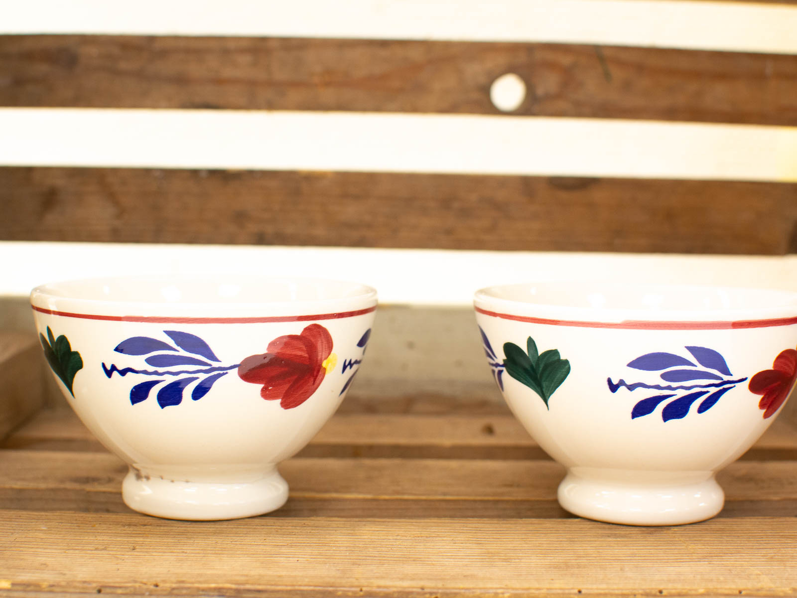 Vibrant hand-painted ceramic bowls on rustic wood, perfect for a charming kitchen display.