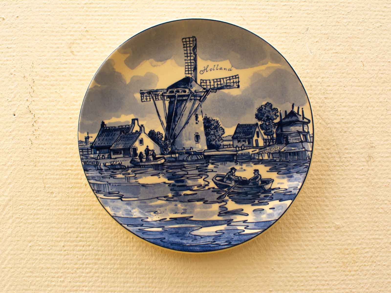 Charming Dutch landscape plate featuring a windmill, cottages, and figures by a tranquil canal.