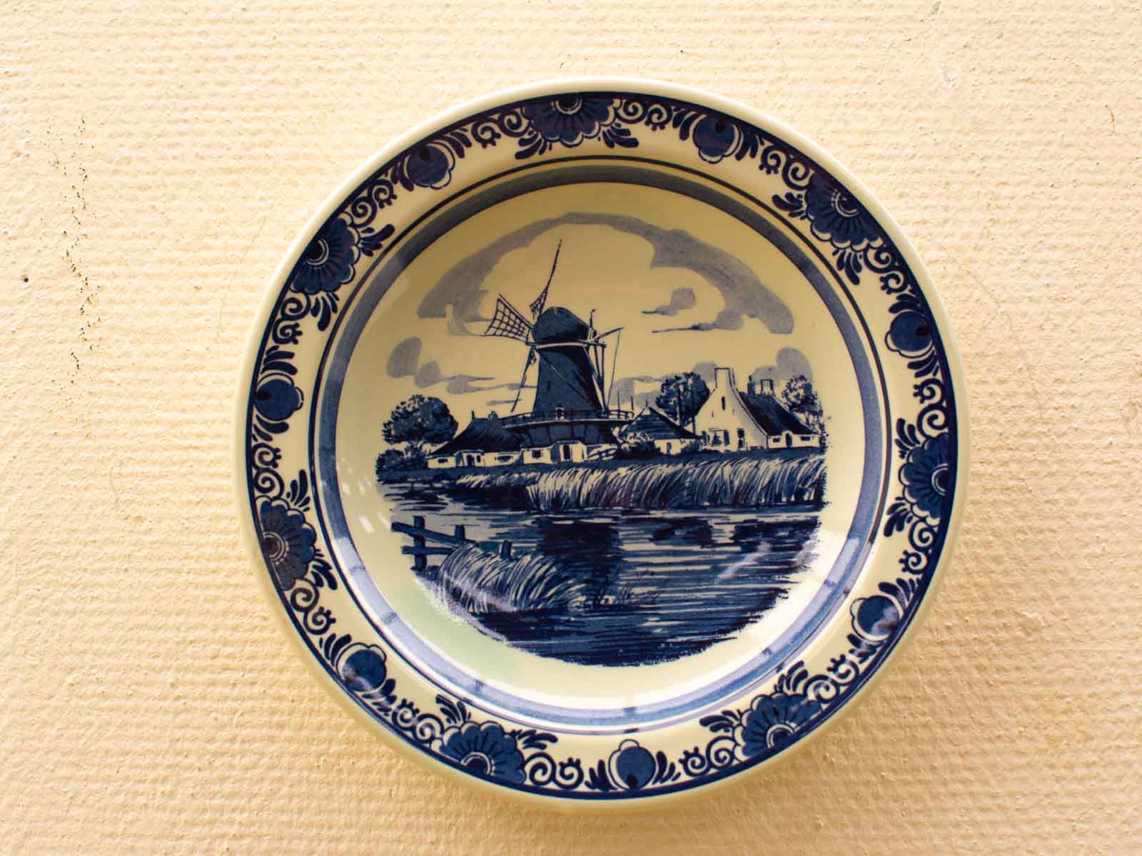 Vintage Dutch ceramic plate with windmill design, showcasing classic blue and white craftsmanship.