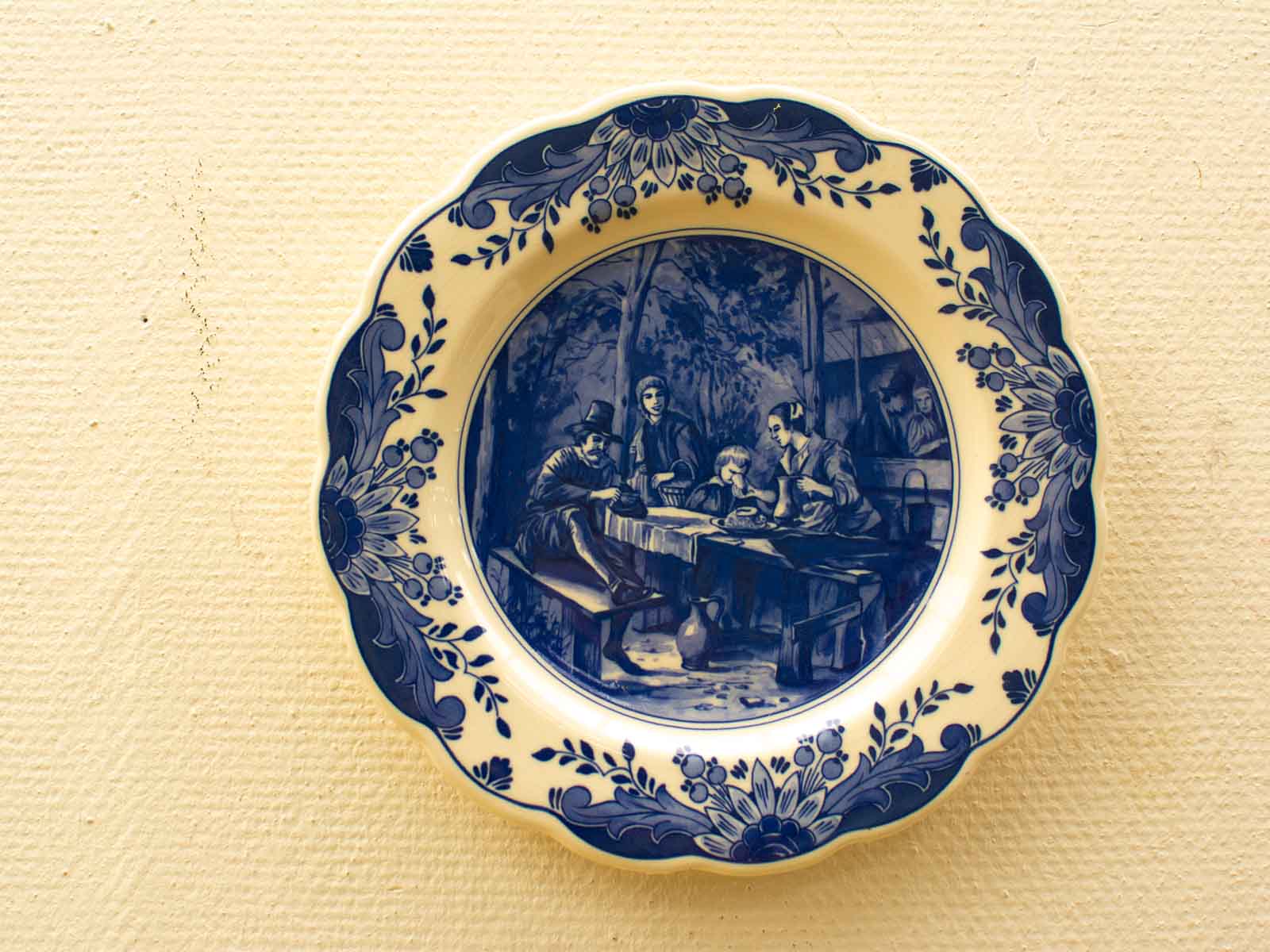 Charming vintage blue and white plate depicting a festive gathering around a table.