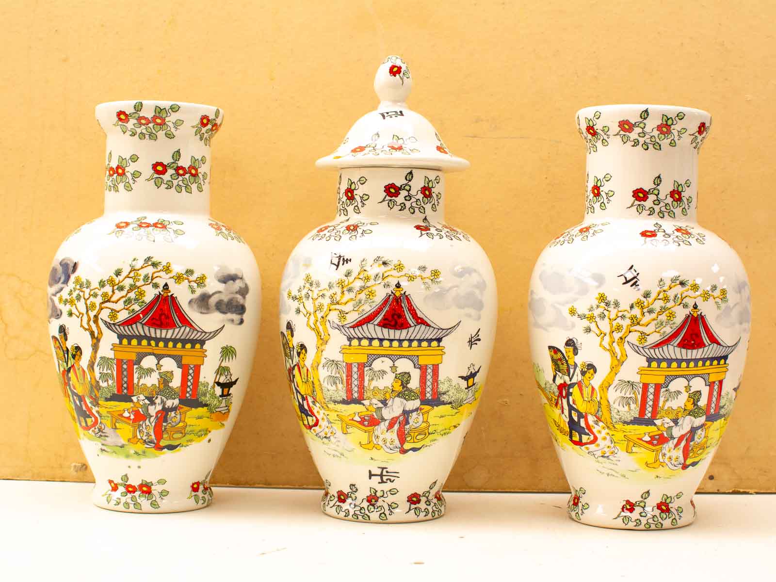 Handcrafted ceramic vases with vibrant traditional motifs and gold accents on a neutral backdrop.