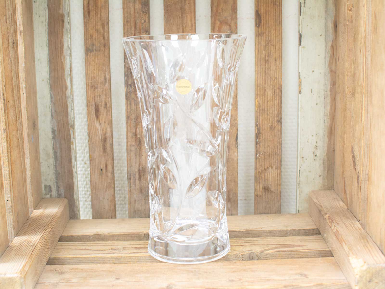 Elegant vintage glass vase with intricate etchings against a rustic wooden backdrop.