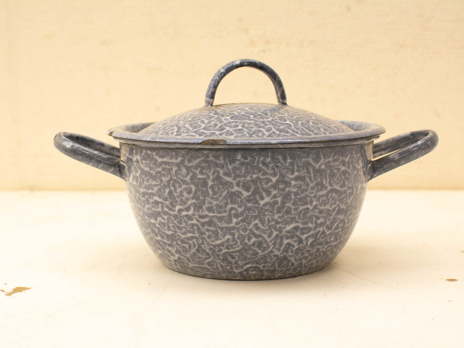 Vintage gray speckled cookware pot with lid, showcasing traditional craftsmanship and nostalgic design.