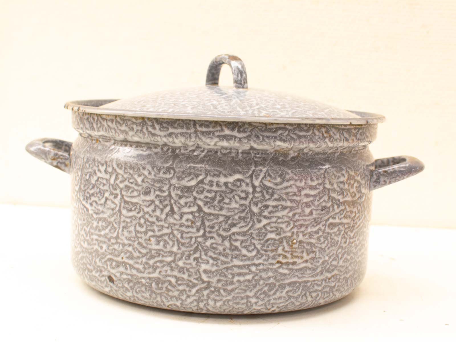 Vintage gray enamel pot with well-worn handles and snug lid, perfect for home-cooked meals.