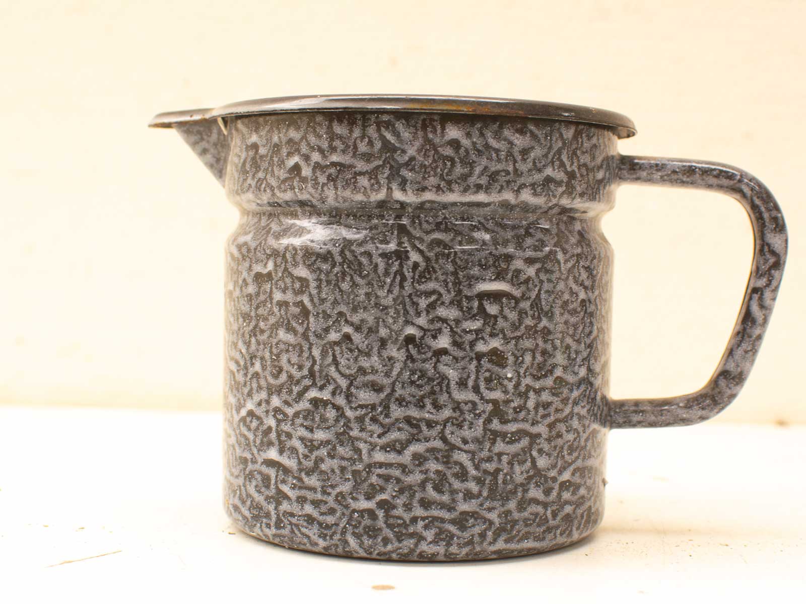 Handmade vintage-style grey metal jug with unique texture and sturdy handle, perfect for rustic decor.