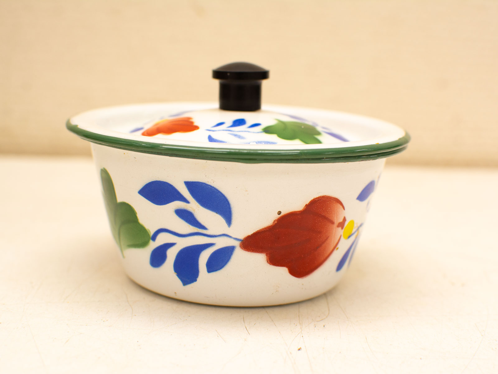 Vibrant hand-painted ceramic bowl with floral design and lid, perfect for display and use.