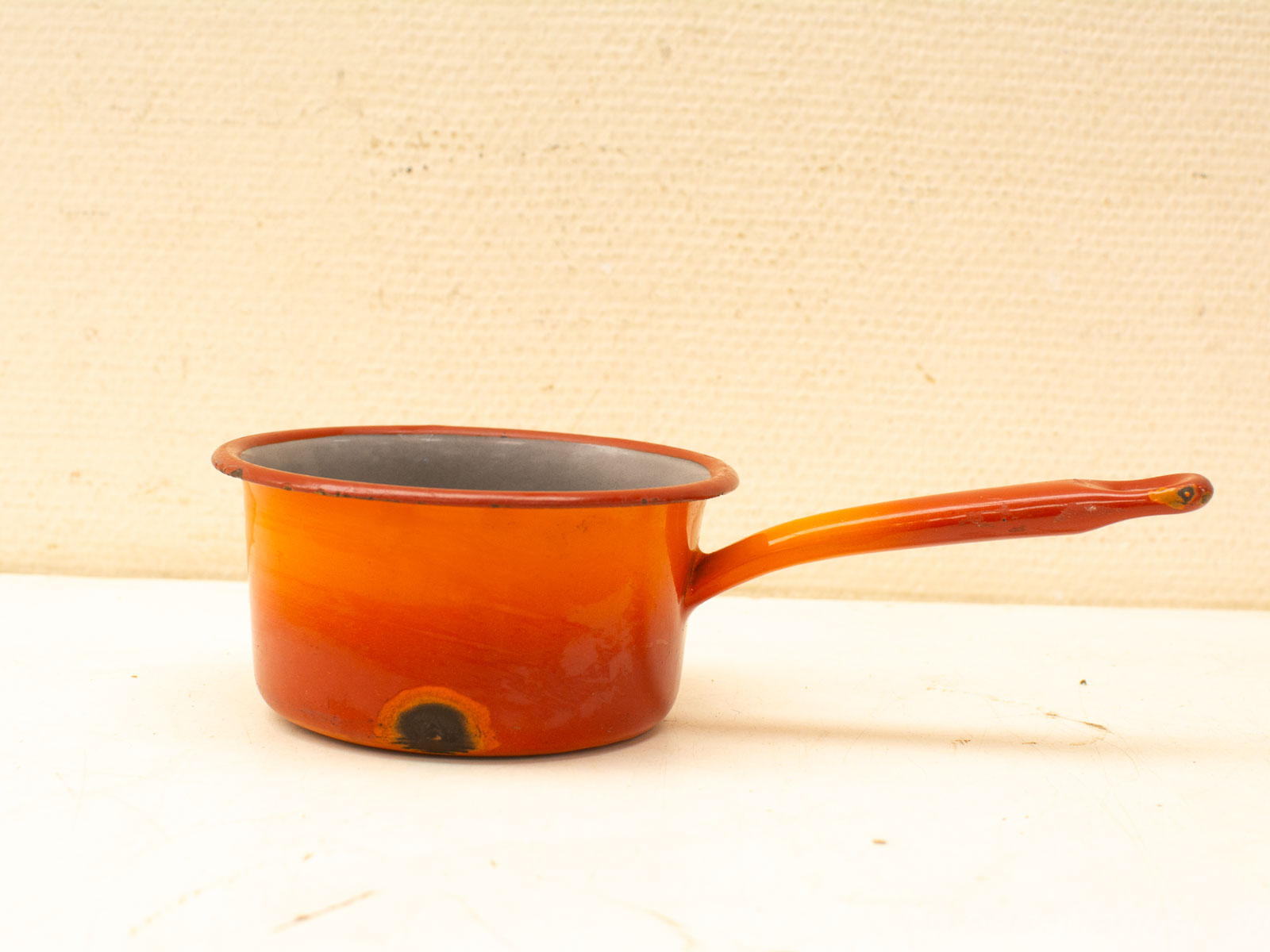 Vintage bright orange cooking pot with dark interior, perfect for traditional home cooking.