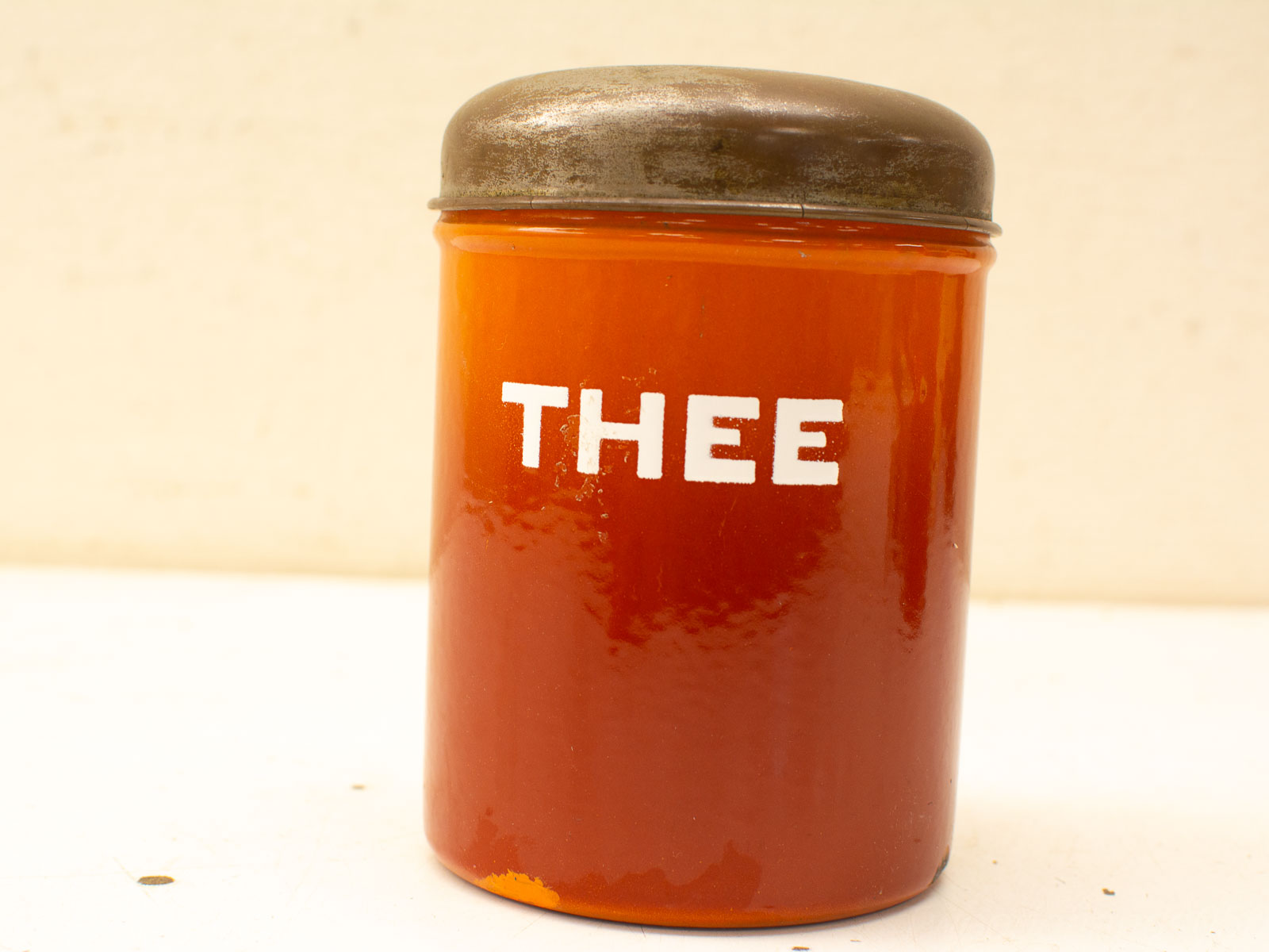 Vintage amber glass tea storage jar with dark metallic lid and bold THEE inscription.