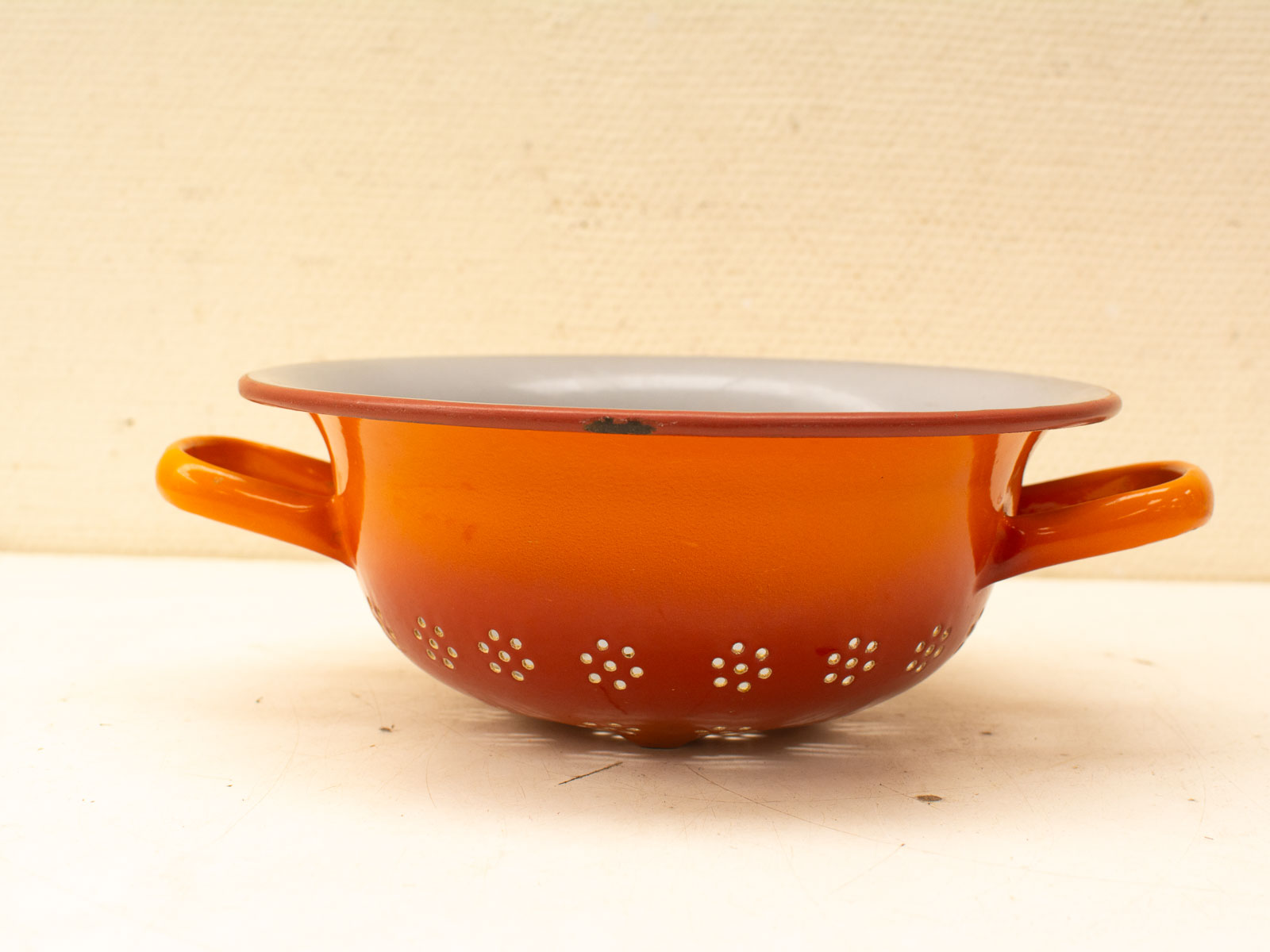 Vintage orange colander with decorative perforations, ideal for draining pasta or vegetables.