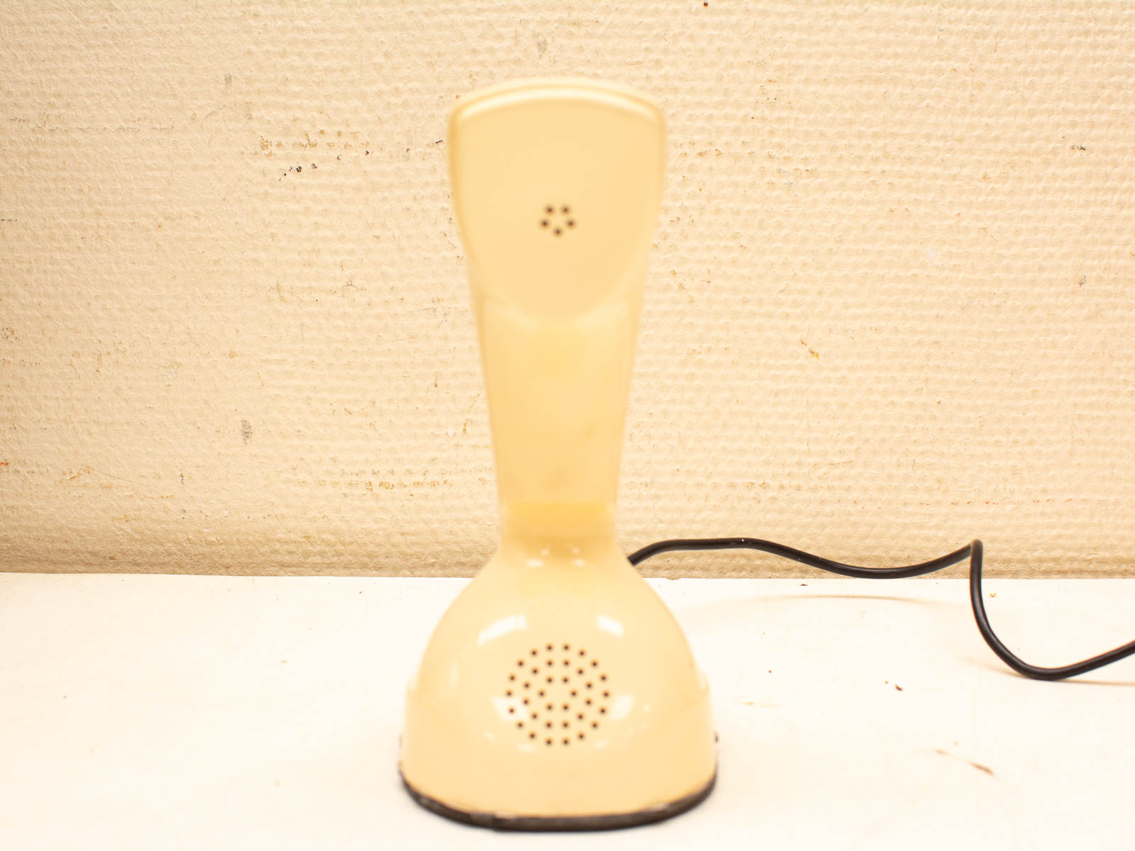 Vintage yellow telephone handset with black cord, perfect for retro decor and nostalgia lovers.