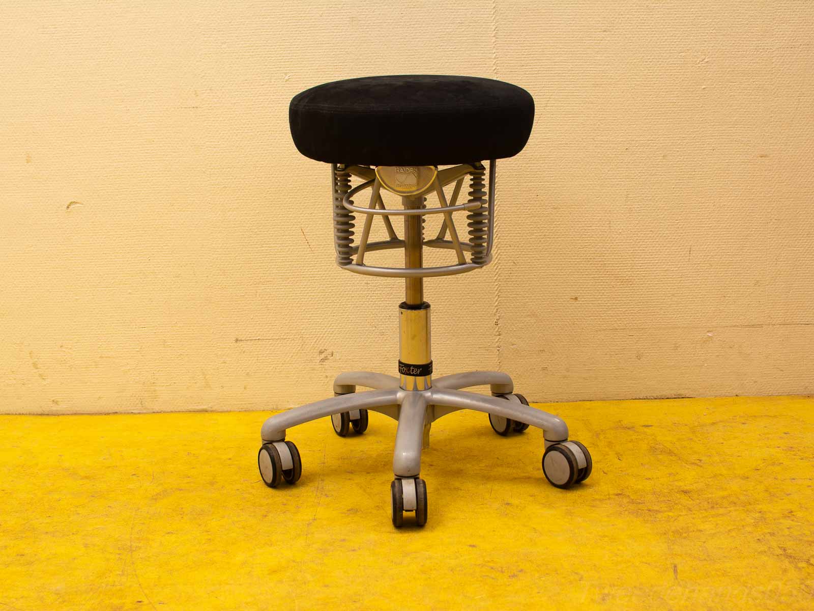 Stylish adjustable stool on wheels with a black seat and silver frame for versatile comfort.