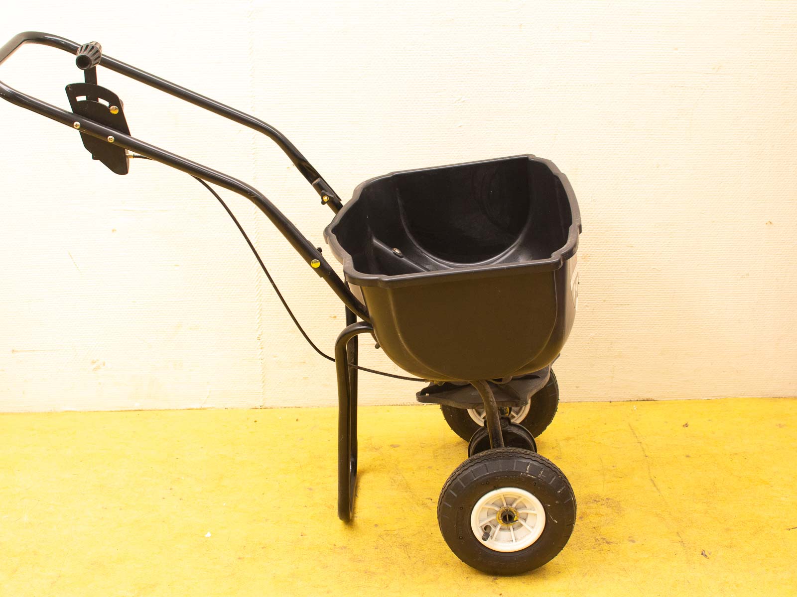 Durable garden spreader with a sturdy hopper, comfortable grip, and smooth-rolling wheels.