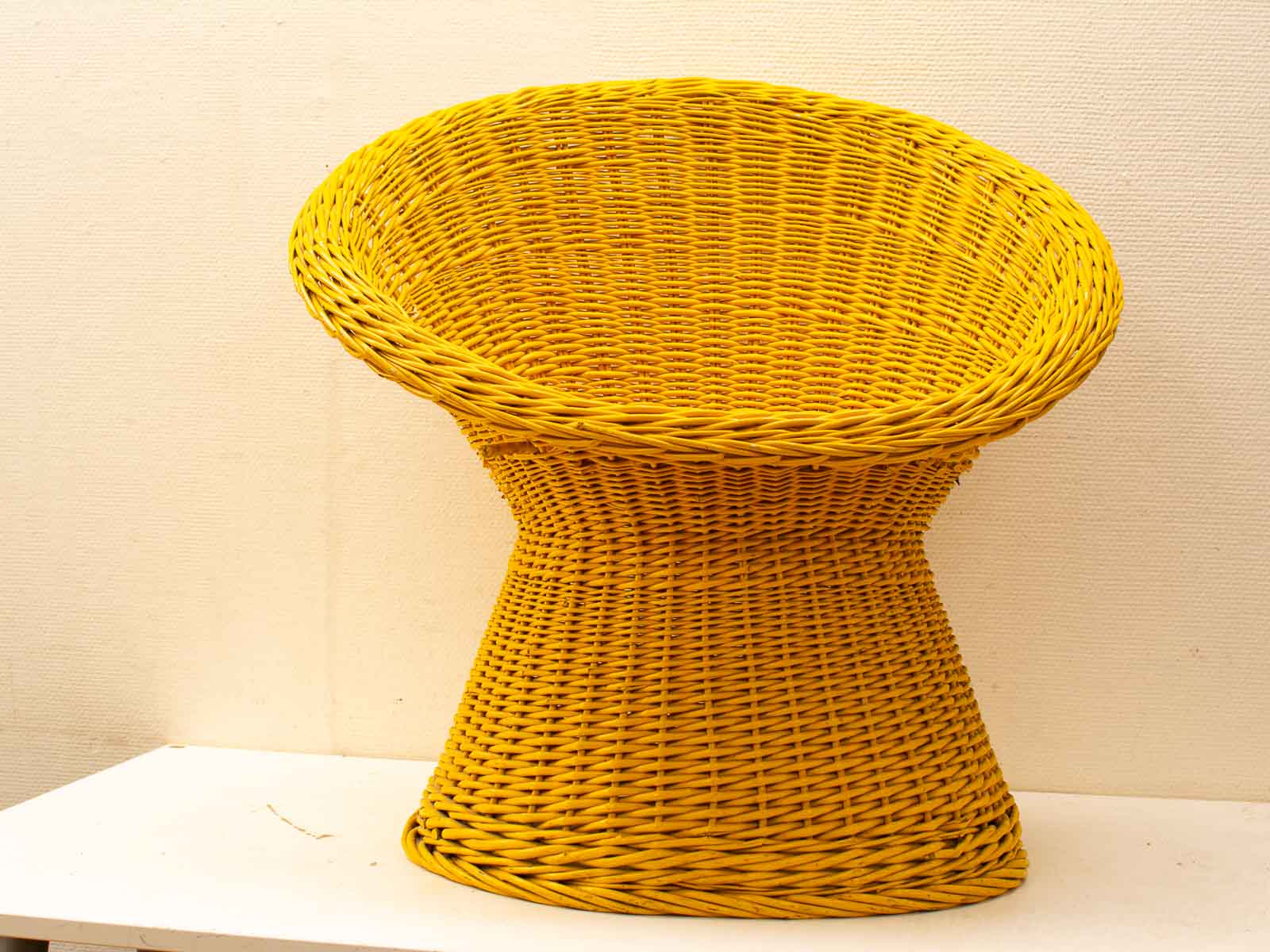 Vibrant yellow woven chair with a unique, ergonomic design for stylish indoor and outdoor comfort.