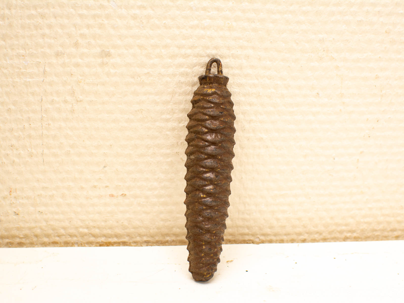 Antique metal pine cone-shaped object with textured surface, perfect for collectors and display.