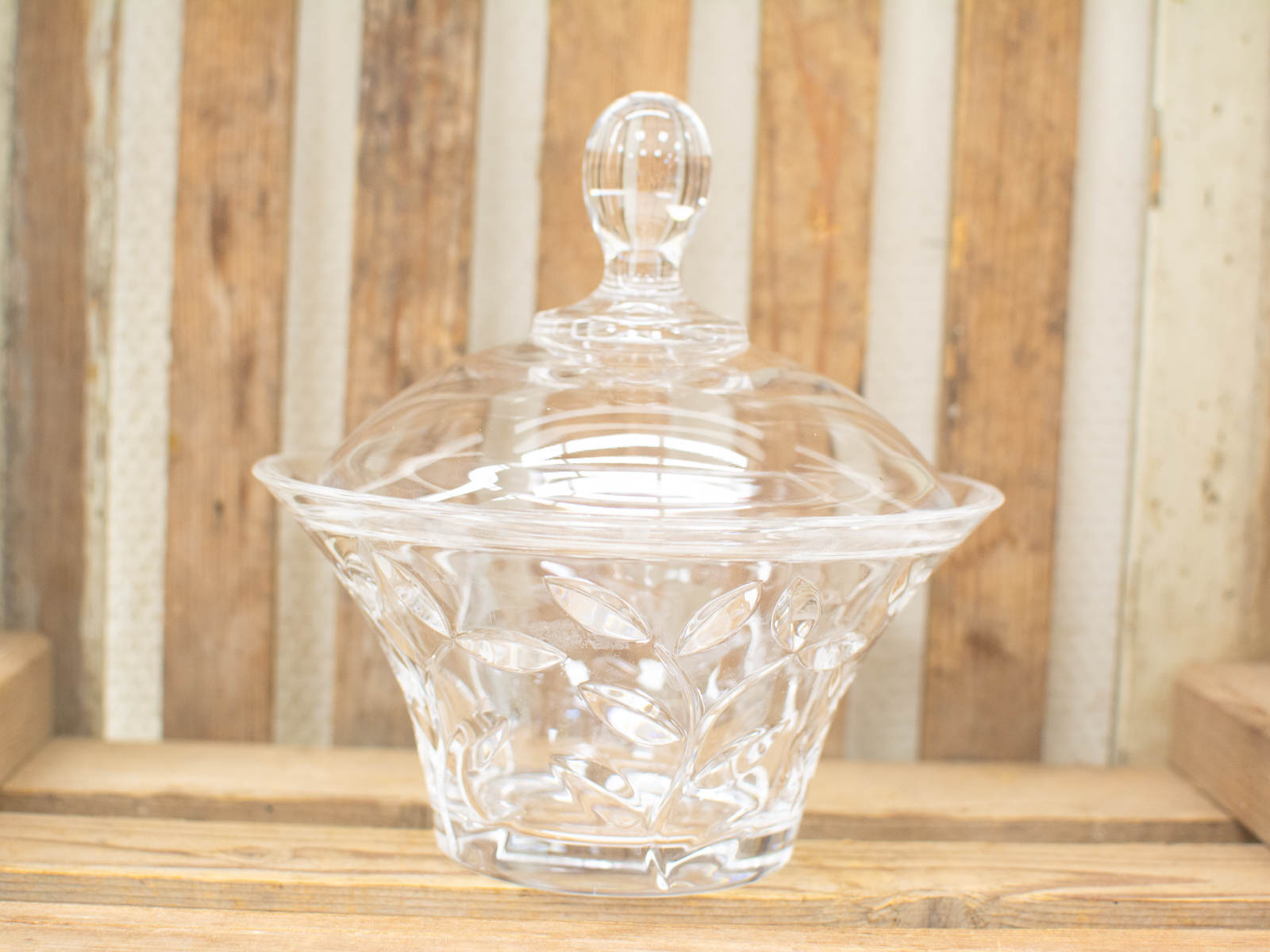 Elegant glass candy dish with etched designs and rustic wooden backdrop for timeless decor.