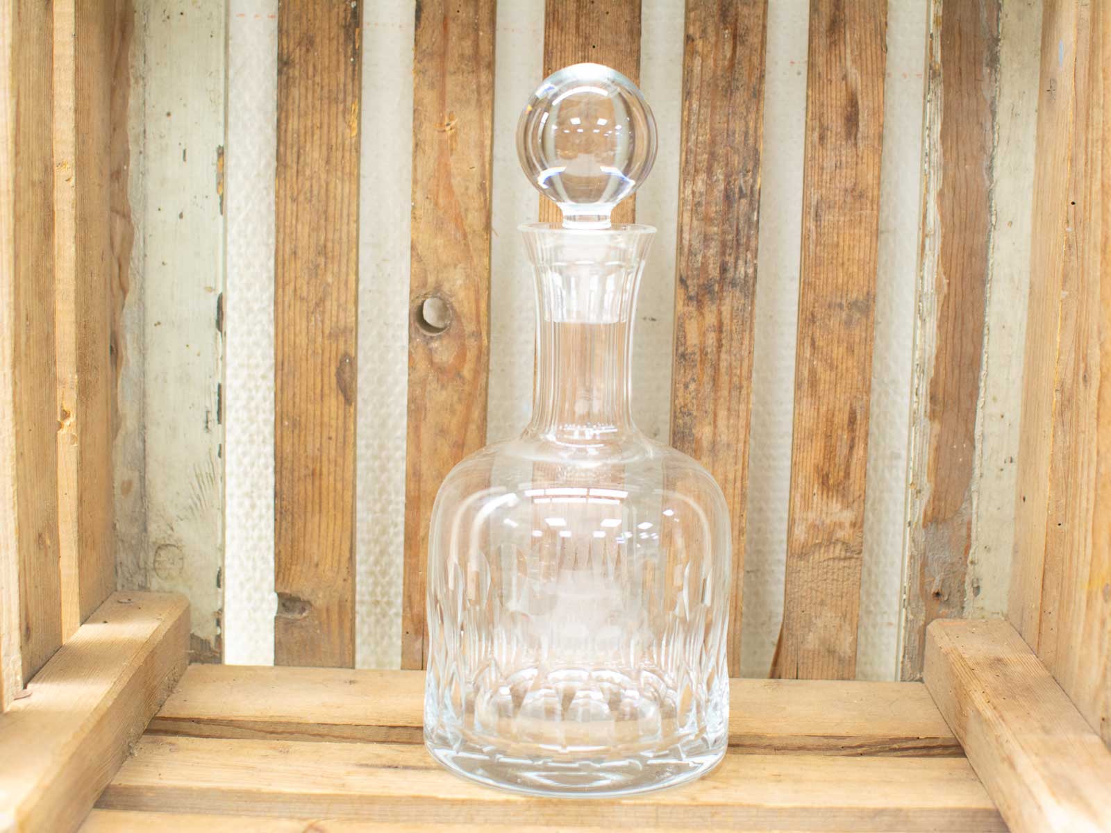 Elegant crystal decanter on rustic wooden background, symbolizing refined taste and sophistication.